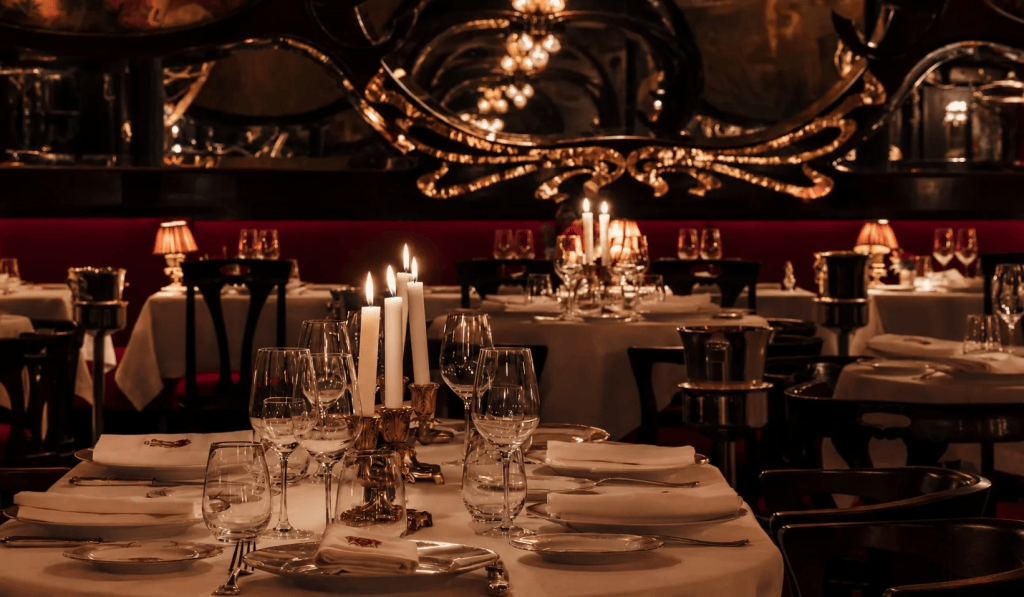 Elegant dining room with white tablecloths, candles, and fine glassware, featuring an upscale, intimate ambiance.