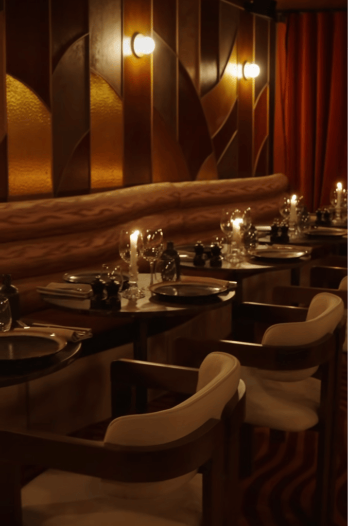 An elegant dining room featuring wooden paneling, soft lighting, and neatly arranged tables with fine dinnerware.